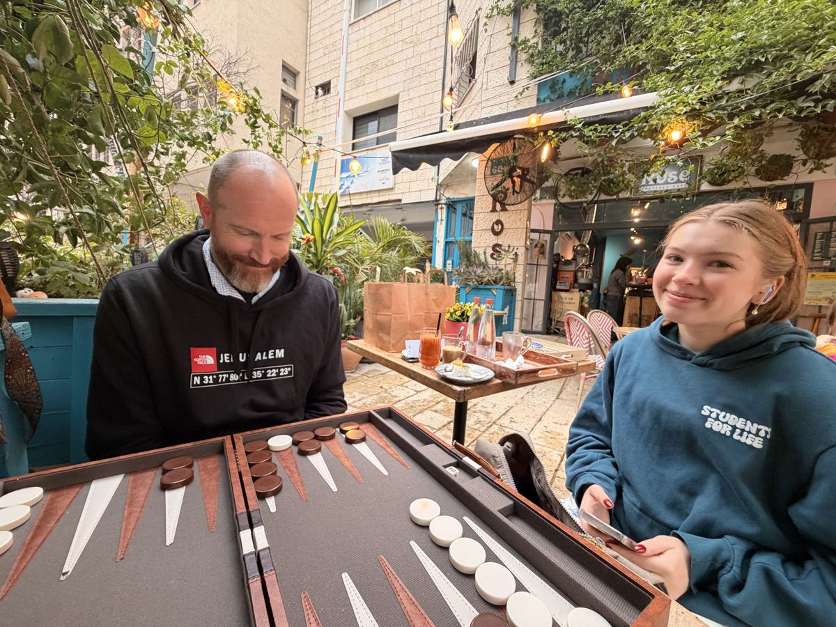 Kevin and their daughter at a backgammon game at an outdoor cafe
