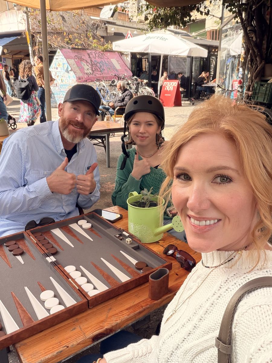 Kevin and their daughter giving a thumbs up at a backgammon game while Tabitha takes a selfie