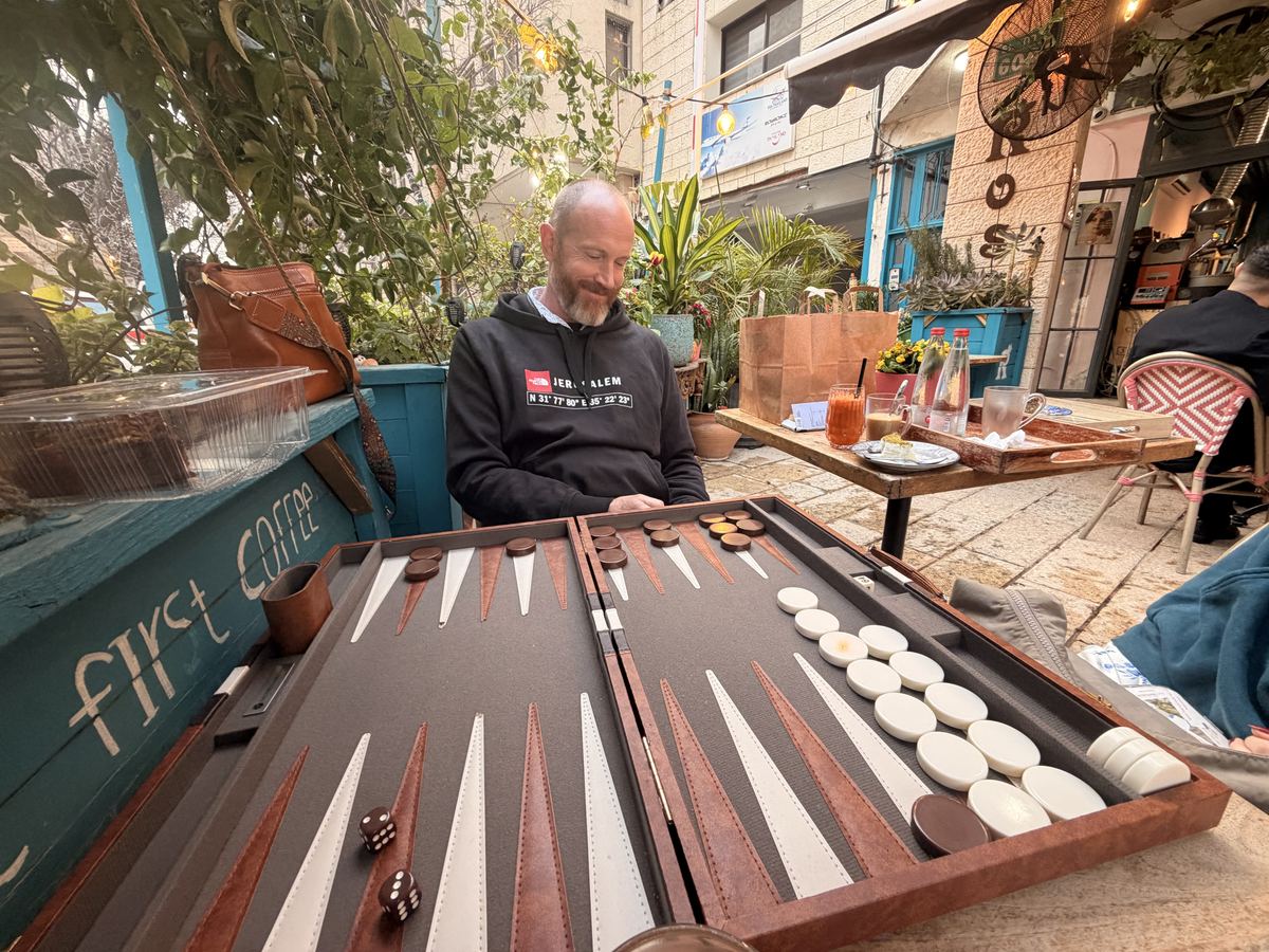 Kevin Lovell playing backgammon at an outdoor coffee shop table