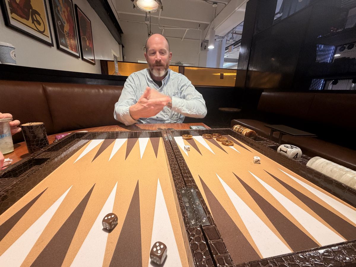 Kevin Lovell rolling the dice at a backgammon board in a restaurant booth