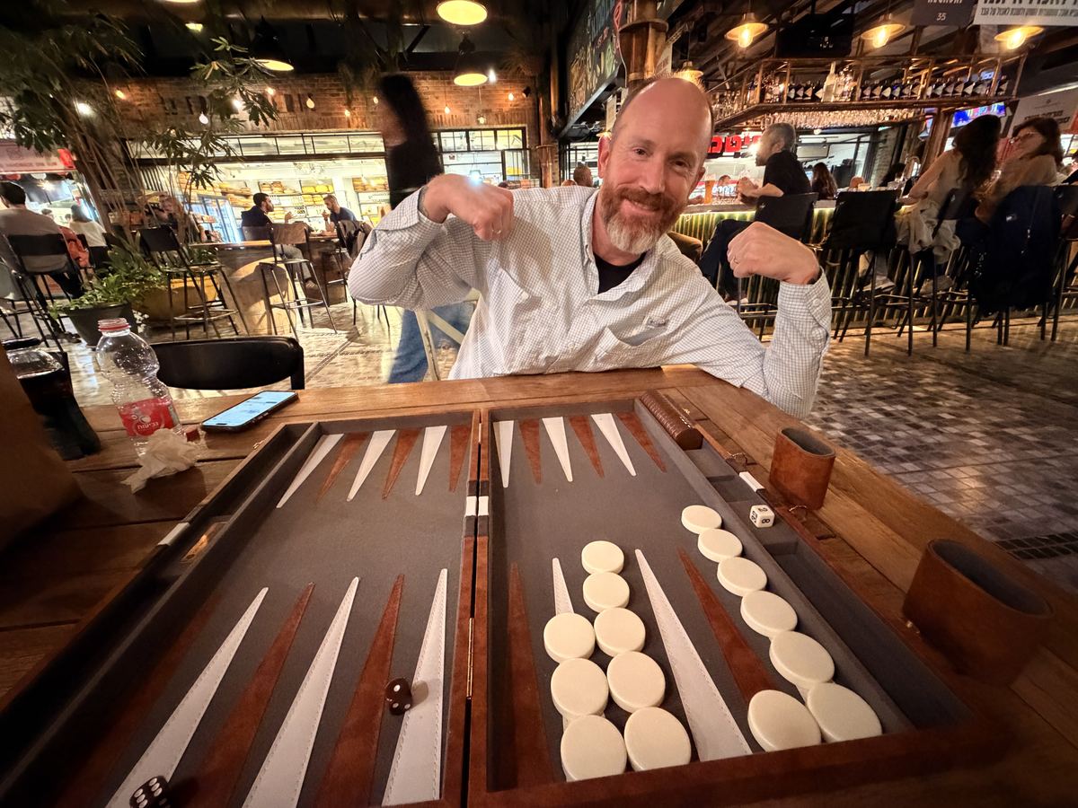 Kevin Lovell flexing behind a backgammon board after a win