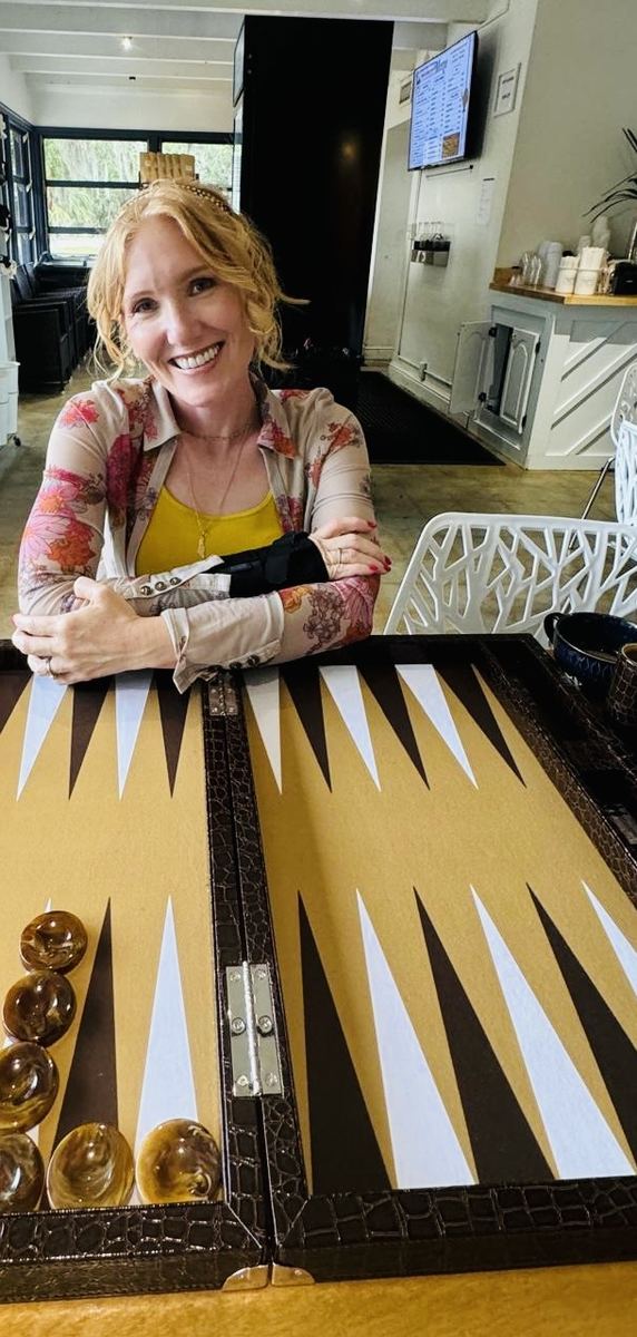 Tabitha Lovell smiling over a backgammon board in a bright cafe