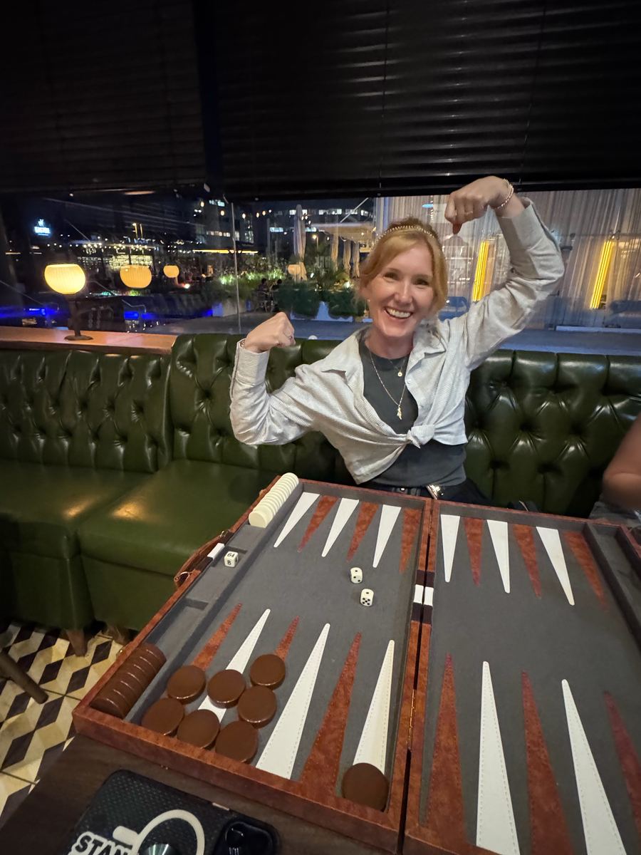 Tabitha Lovell flexing victoriously behind a backgammon board at night